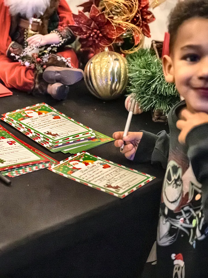 A boy smiling while writing his letter to Santa
