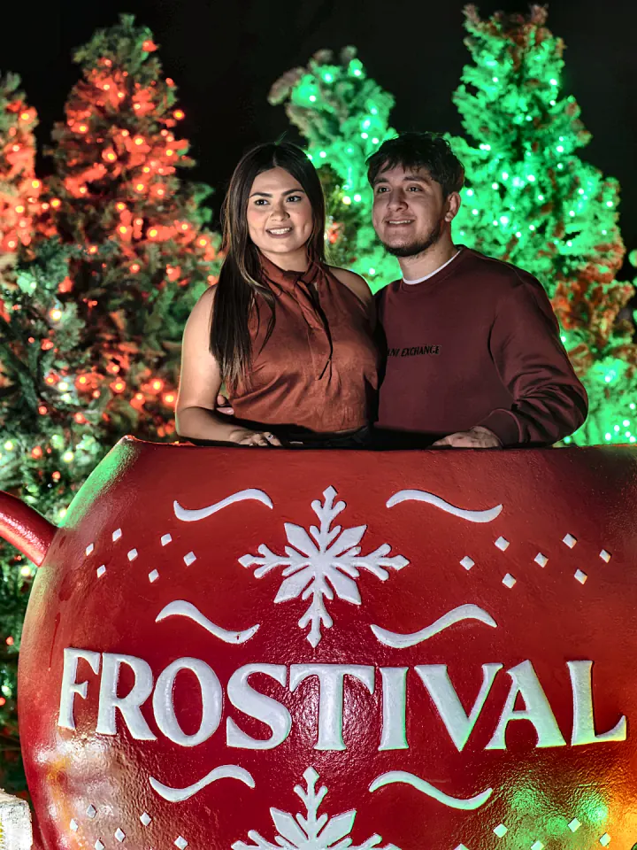 A family behind the giant Frostival ornament sign