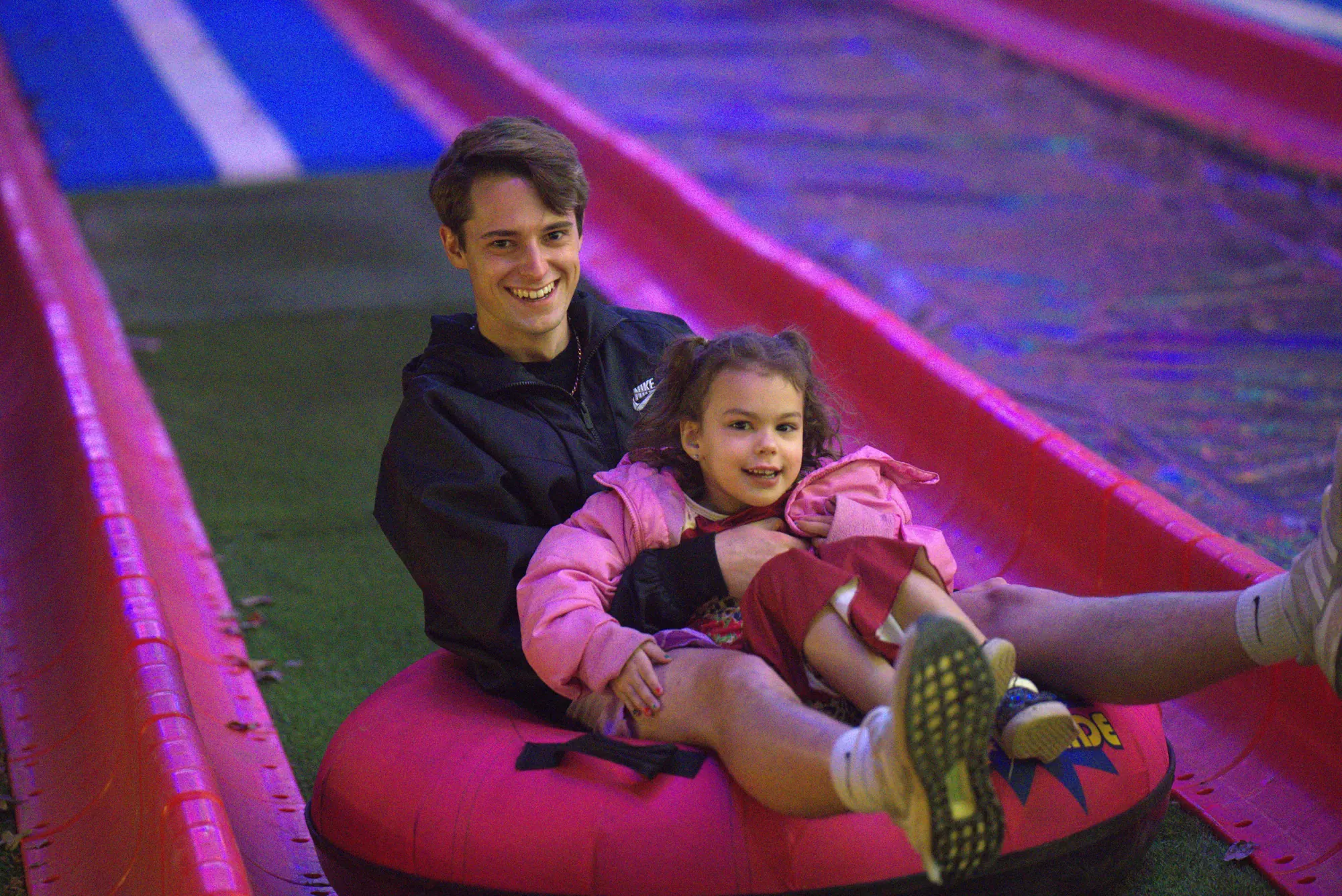 A dad and his daughter laughing on a tube on the 200-foot holiday slide