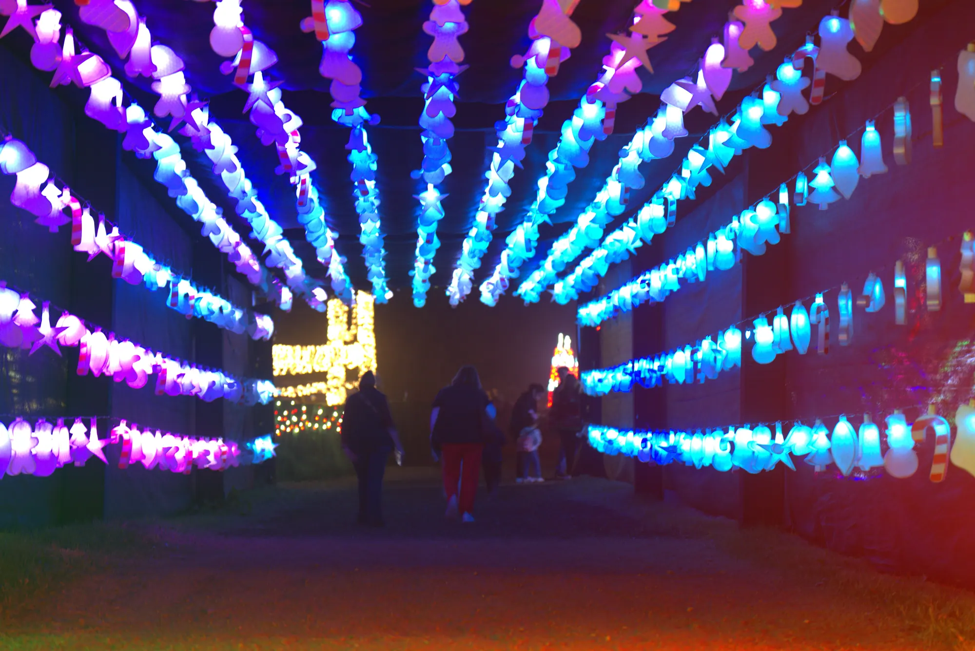 Guests walking through a tunnel of glowing purple and blue lights